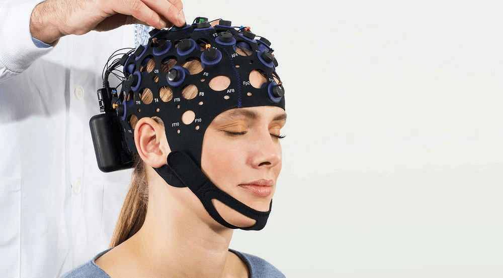 Mujer usando el sistema Versatile EEG con sensores y un amplificador en la parte posterior.