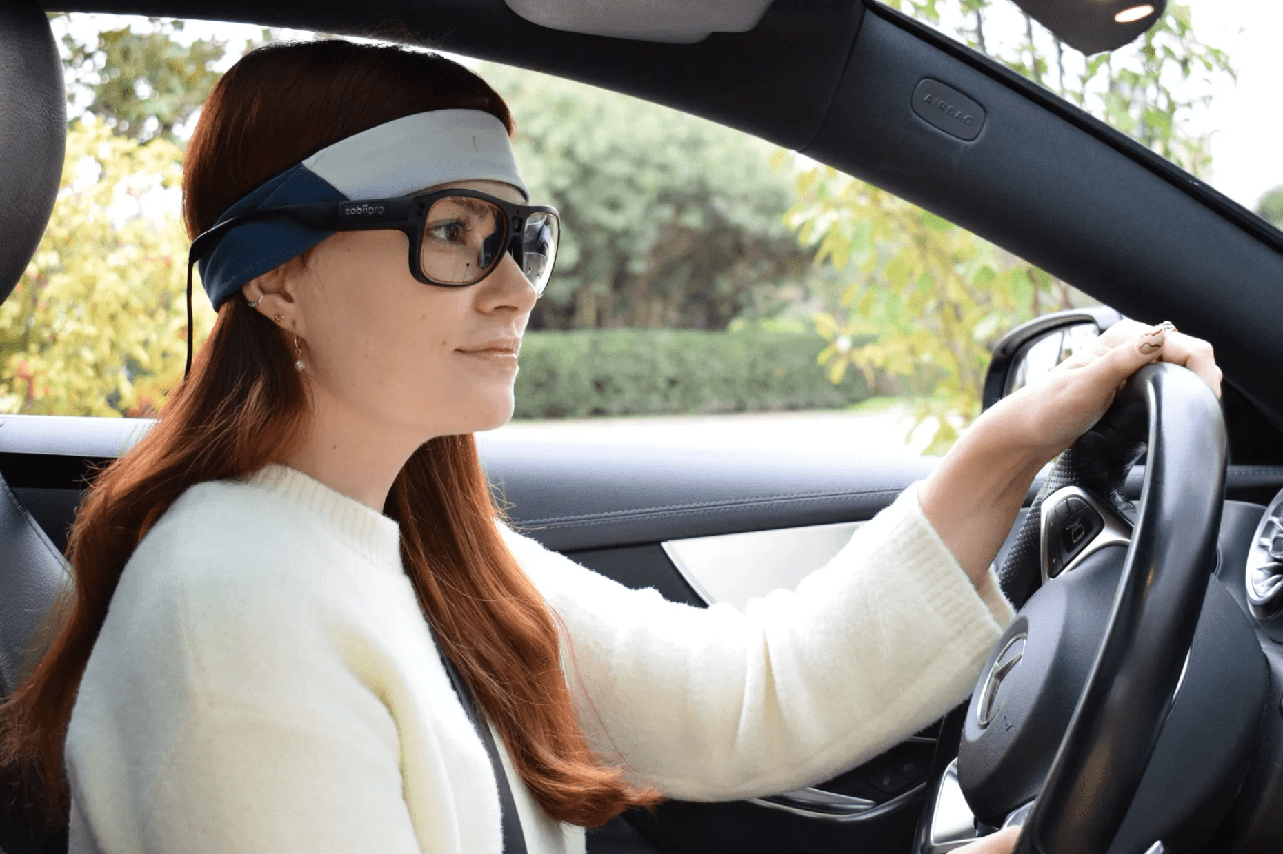 Participant using Bitbrain Ikon textile EEG and Tobii Pro Glasses eye tracking technology during a driving simulation and human behavior research study.