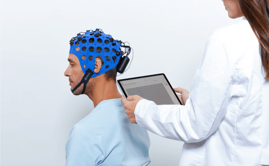 Investigador revisando datos de actividad cerebral en una pantalla mientras un participante lleva puesto el sistema Bitbrain Versatile EEG.