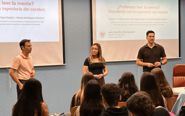 Presenters delivering an educational talk to a group of students in a classroom, explaining neuroscience and electroencephalography (EEG) concepts with projected slides.