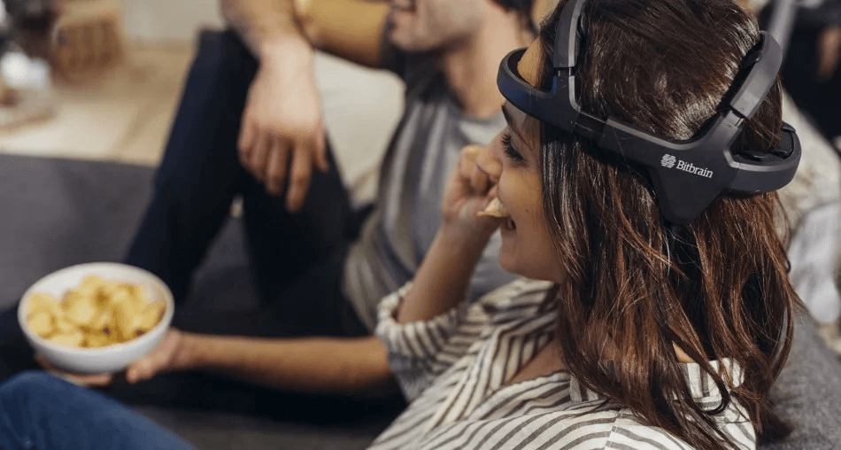 Illustration of a woman wearing the Bitbrain Diadem EEG device while watching television.