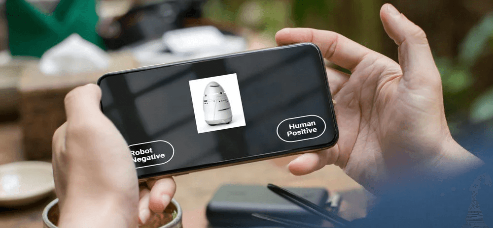 Persona sosteniendo un teléfono móvil que muestra una tarea de clasificación de un Test de Asociación Implícita (IAT), en la que una imagen de un robot debe asociarse con categorías positivas o negativas.